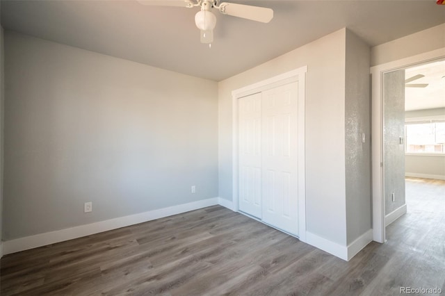 unfurnished bedroom featuring a closet, ceiling fan, baseboards, and wood finished floors