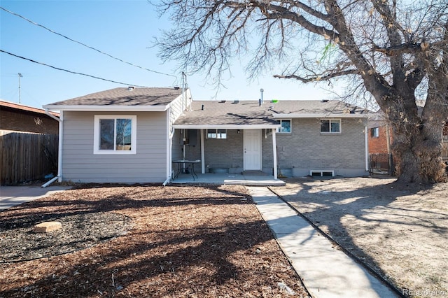 back of property featuring covered porch, fence, and brick siding