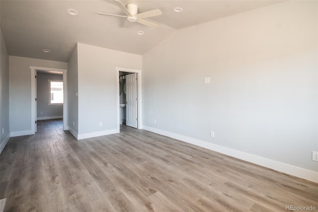 empty room with a ceiling fan, lofted ceiling, baseboards, and wood finished floors