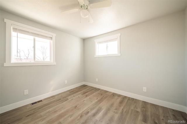 empty room featuring light wood-style flooring, visible vents, and baseboards