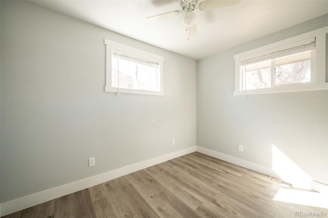 empty room with a ceiling fan, baseboards, visible vents, and wood finished floors