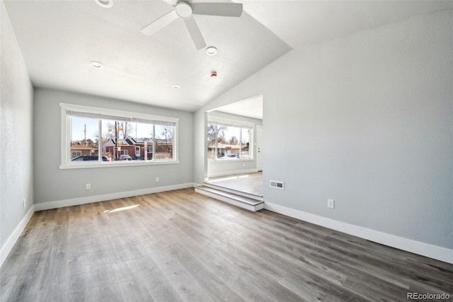 spare room featuring baseboards, visible vents, a ceiling fan, wood finished floors, and vaulted ceiling