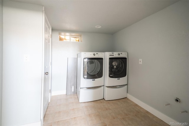 washroom featuring baseboards, washing machine and clothes dryer, and light tile patterned floors