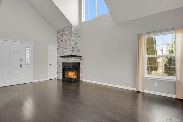 unfurnished living room featuring dark hardwood / wood-style flooring, a fireplace, and high vaulted ceiling