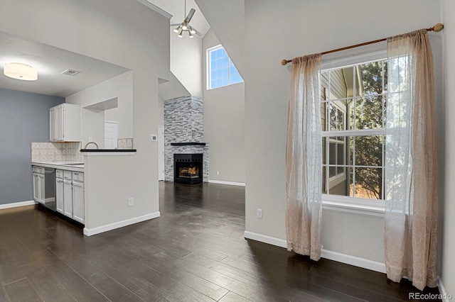 kitchen with a stone fireplace, decorative backsplash, white cabinets, and dark hardwood / wood-style floors