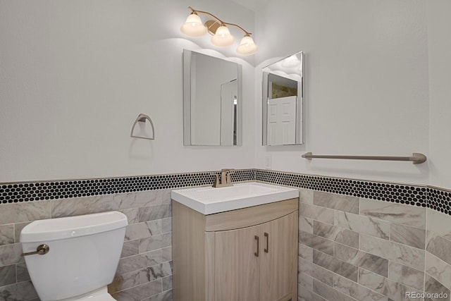 bathroom featuring vanity, toilet, and tile walls