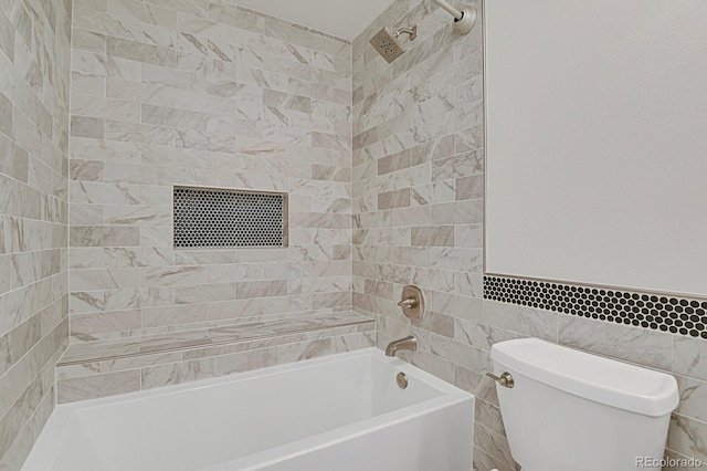 bathroom featuring tiled shower / bath, tile walls, and toilet