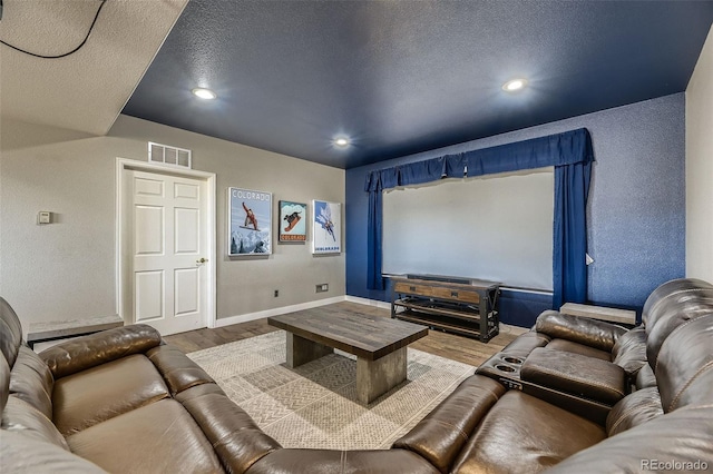 11549 Haskell Creek Rd, Larkspur, CO 80118 - home theater room with wood finished floors, a textured ceiling, baseboards, a textured wall, and recessed lighting