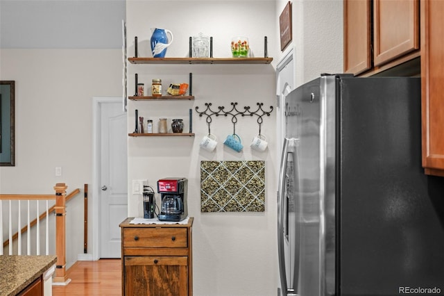 kitchen featuring stainless steel fridge, light hardwood / wood-style flooring, and stone counters