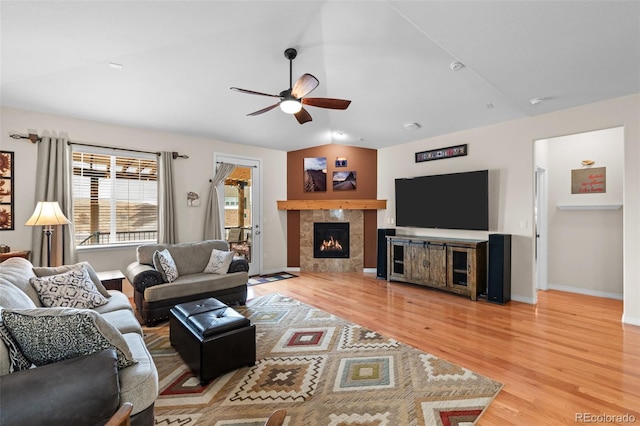 living room with ceiling fan, lofted ceiling, a tile fireplace, and wood-type flooring