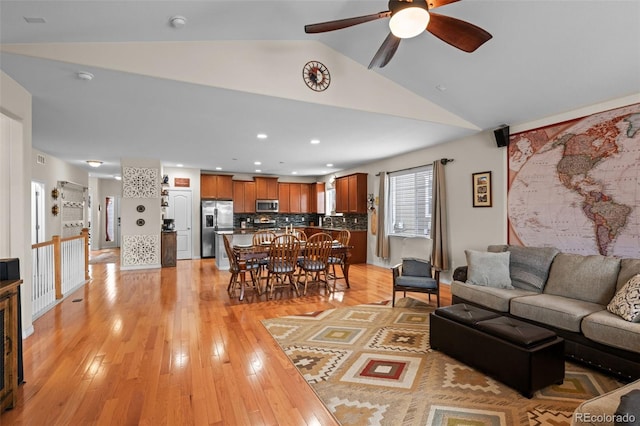 living room featuring lofted ceiling, ceiling fan, and light hardwood / wood-style flooring