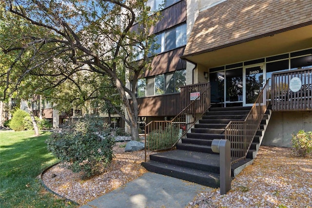 property entrance with a yard and roof with shingles