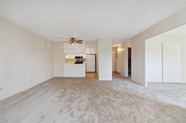 unfurnished living room featuring light colored carpet, a textured ceiling, and ceiling fan