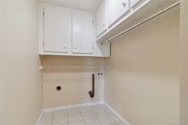 laundry area with hookup for an electric dryer, light tile patterned floors, and cabinets