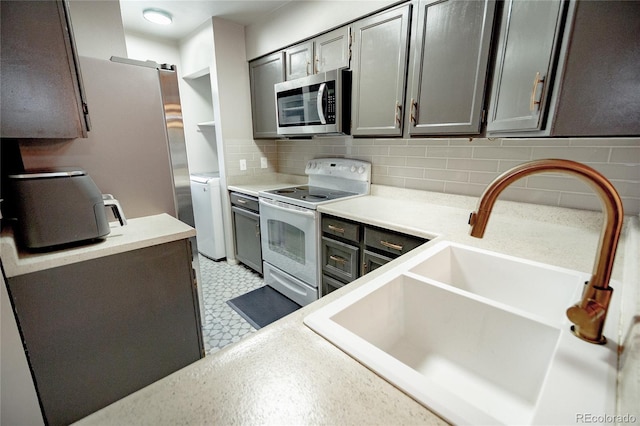 1699 S Trenton St Unit 69, Denver, CO 80231 - kitchen featuring stainless steel appliances, light flooring, gray cabinets, tasteful backsplash, and light countertops