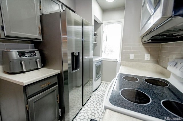 1699 S Trenton St Unit 69, Denver, CO 80231 - kitchen with appliances with stainless steel finishes, backsplash, light countertops, and washer / dryer