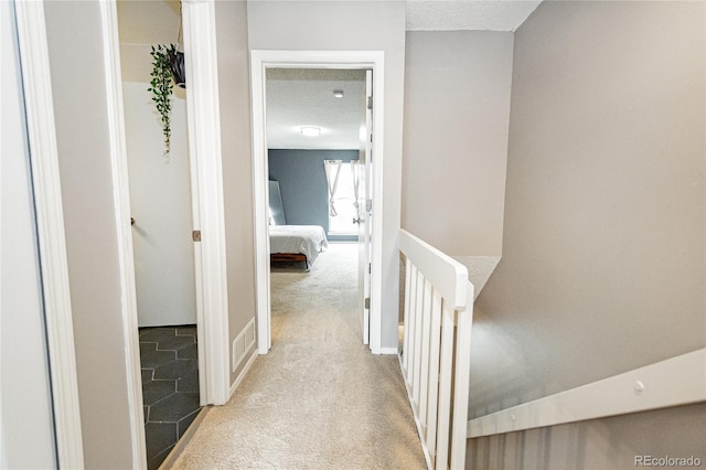 1699 S Trenton St Unit 69, Denver, CO 80231 - hall featuring carpet flooring, a textured ceiling, and an upstairs landing