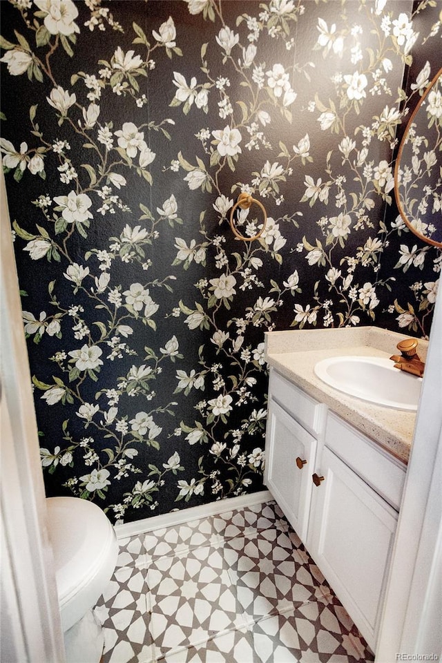 1699 S Trenton St Unit 69, Denver, CO 80231 - half bathroom featuring vanity, tile patterned floors, and wallpapered walls