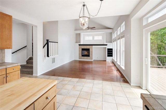 4488 Larksong Pl, Castle Rock, CO 80109 - unfurnished living room with stairway, lofted ceiling, light wood finished floors, a chandelier, and a tile fireplace