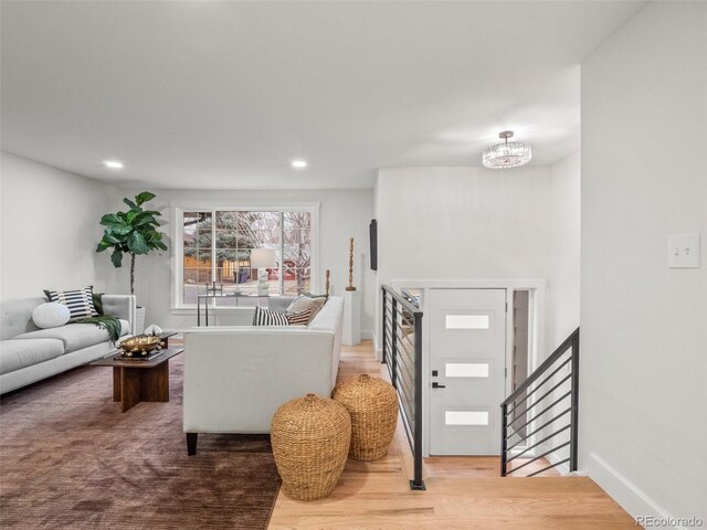 living area with wood finished floors, recessed lighting, stairway, baseboards, and a chandelier