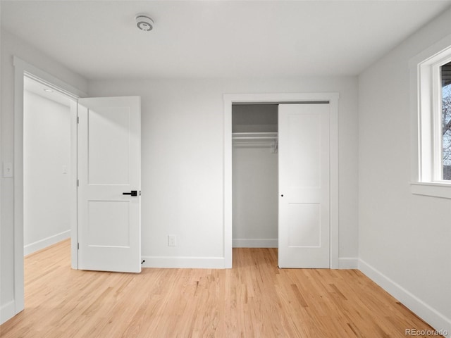 unfurnished bedroom featuring a closet, baseboards, and light wood-style flooring