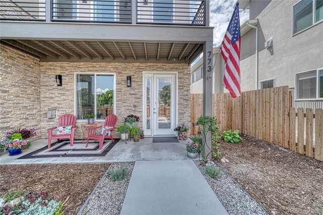 entrance to property with a patio area, fence, and a balcony