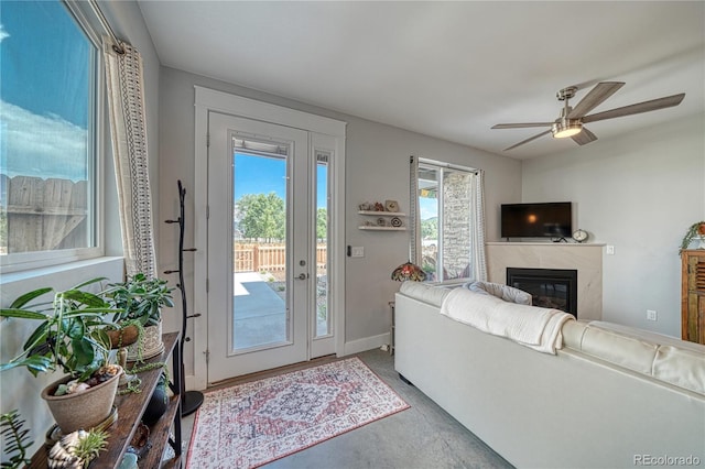 living room featuring concrete floors, a fireplace, baseboards, and a ceiling fan