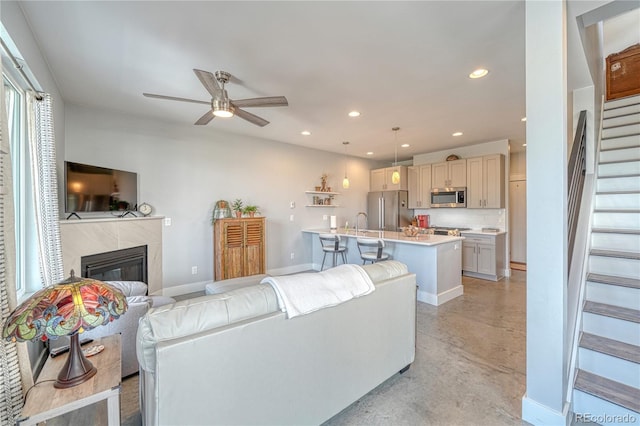 living room with finished concrete flooring, recessed lighting, stairway, a premium fireplace, and baseboards