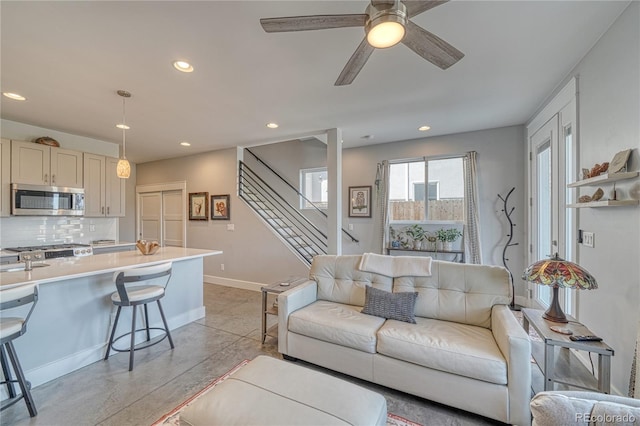 living room with baseboards, ceiling fan, stairway, finished concrete floors, and recessed lighting