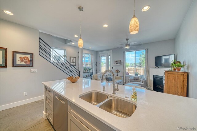 kitchen with a fireplace with flush hearth, a sink, hanging light fixtures, and dishwasher