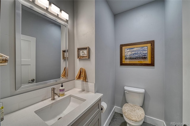 half bathroom with vanity, toilet, and baseboards