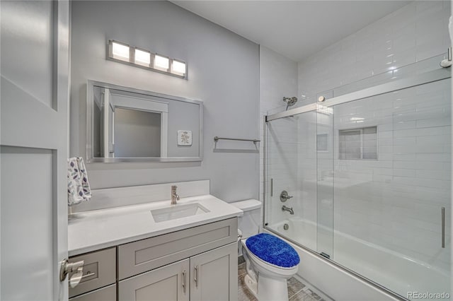 full bathroom with shower / bath combination with glass door, vanity, and toilet