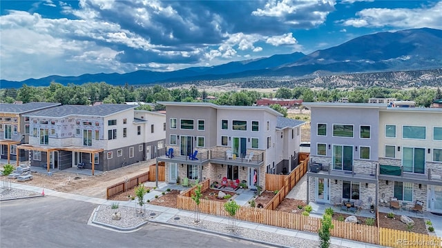 exterior space featuring stone siding, a fenced front yard, a patio area, and a mountain view