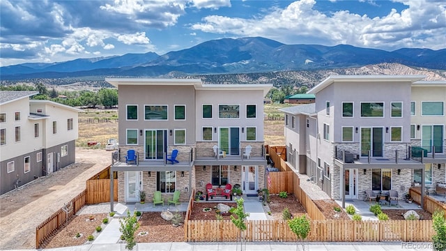 view of front facade featuring a fenced front yard, stone siding, a mountain view, and stucco siding