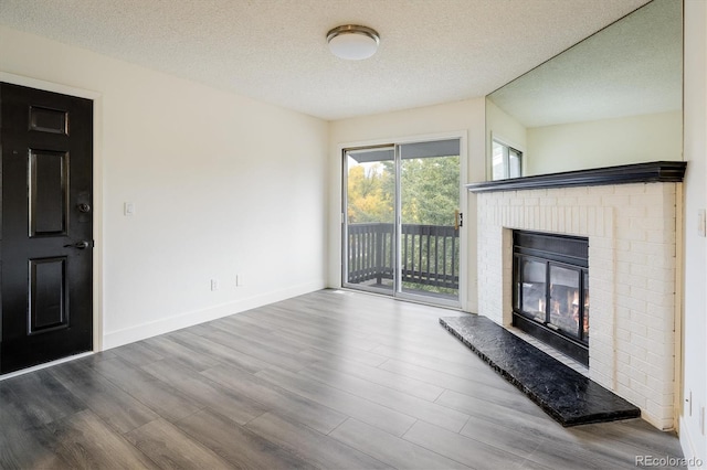 unfurnished living room featuring a fireplace, a textured ceiling, and hardwood / wood-style flooring