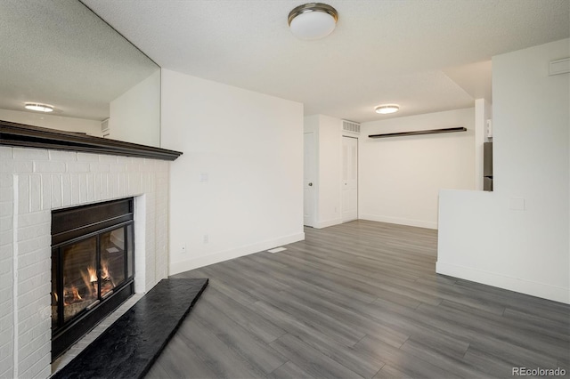 unfurnished living room featuring a textured ceiling, a fireplace, and dark hardwood / wood-style floors