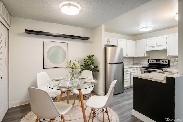 kitchen with white cabinets, stainless steel appliances, and hardwood / wood-style floors