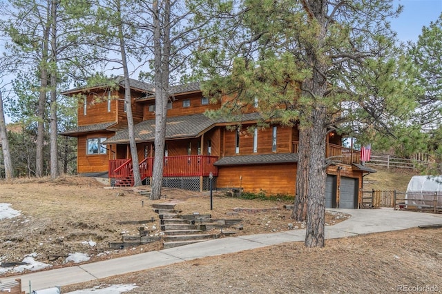 chalet / cabin featuring driveway, an attached garage, and fence