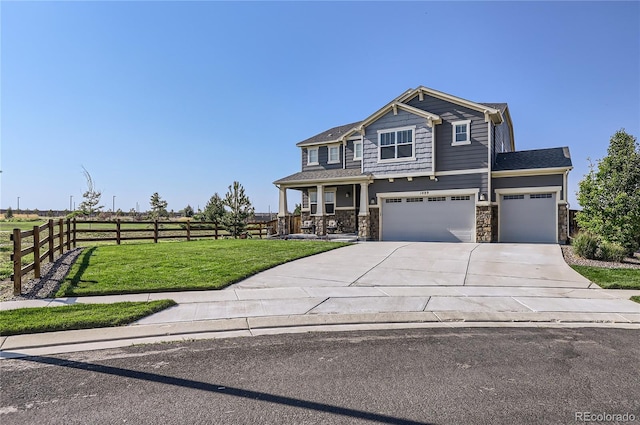 craftsman house with fence, a front yard, a garage, stone siding, and driveway