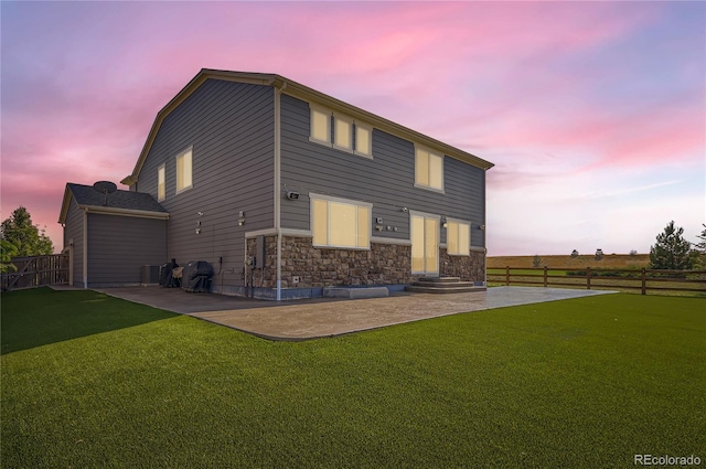 view of front facade featuring a patio, fence, a front lawn, and stone siding