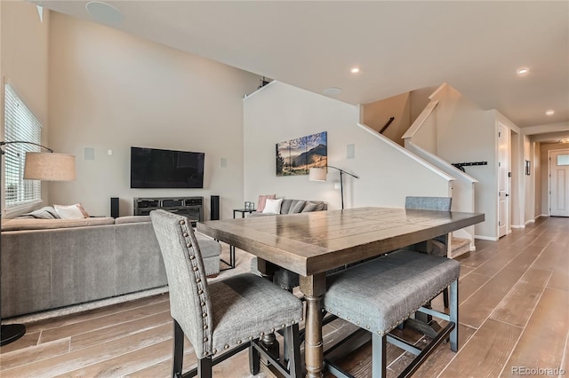 dining space with recessed lighting, baseboards, wood finished floors, and stairs