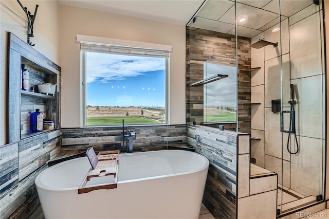 full bath featuring tile walls, a freestanding tub, and a stall shower