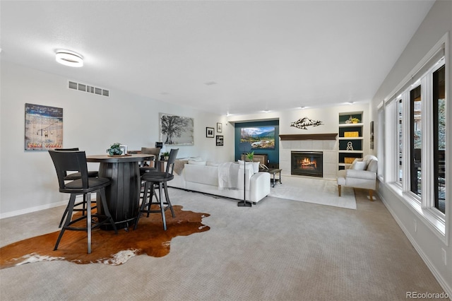 living area with carpet, visible vents, a fireplace, and baseboards