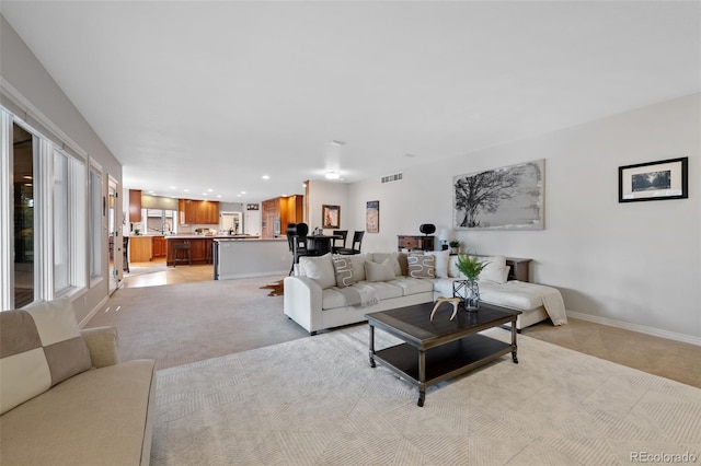 living area with light carpet, recessed lighting, visible vents, and baseboards