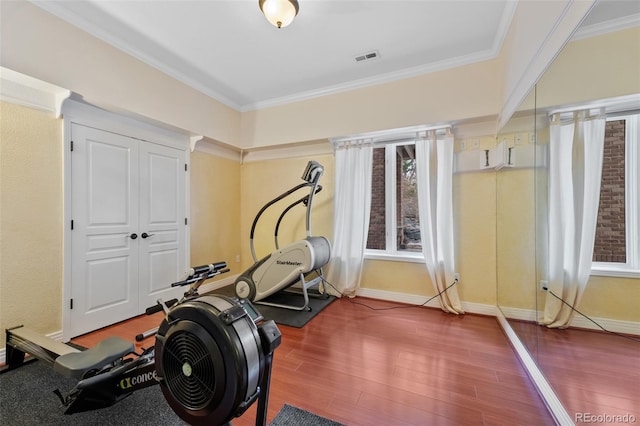 exercise area with ornamental molding, wood finished floors, visible vents, and baseboards