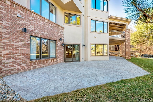 rear view of property featuring brick siding, a patio, and stucco siding