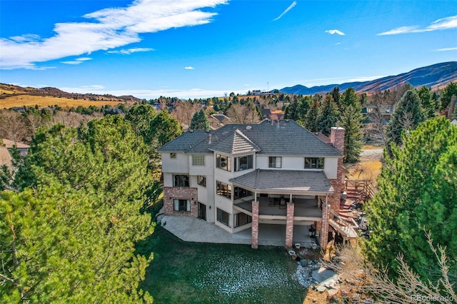 rear view of house with a patio, a chimney, stairs, a mountain view, and stucco siding