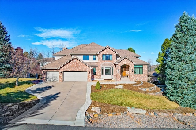 view of front of home with brick siding, a chimney, an attached garage, a front yard, and driveway