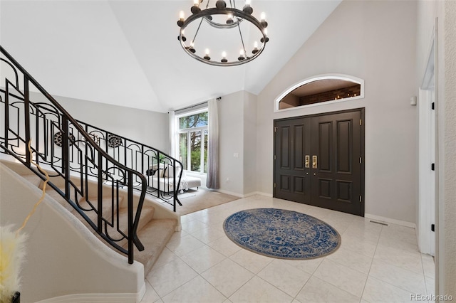 tiled foyer entrance with baseboards, stairs, high vaulted ceiling, and a notable chandelier