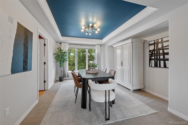 dining space featuring light carpet, baseboards, a raised ceiling, crown molding, and a chandelier